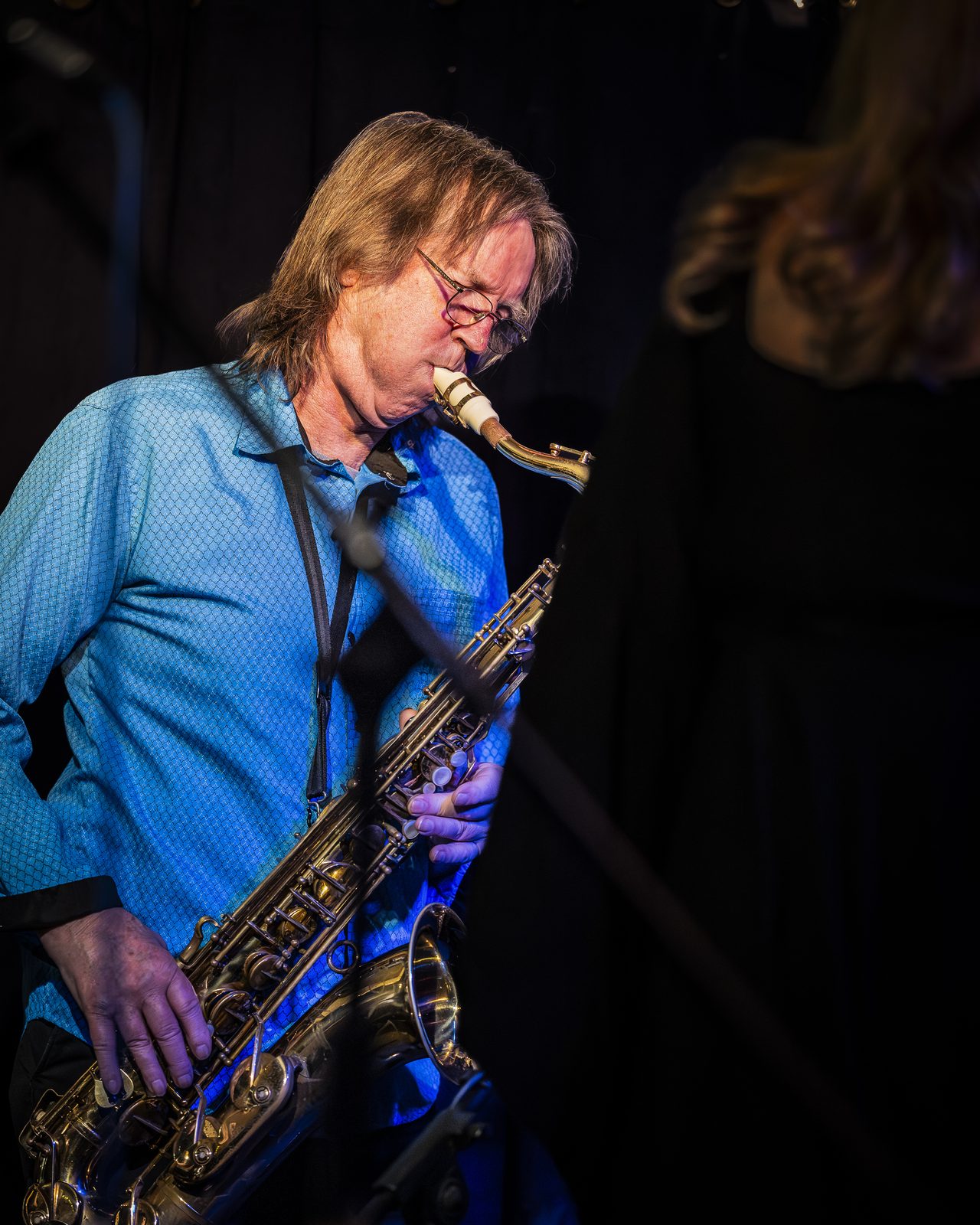Dave Rowse playing saxophone in blue stage light